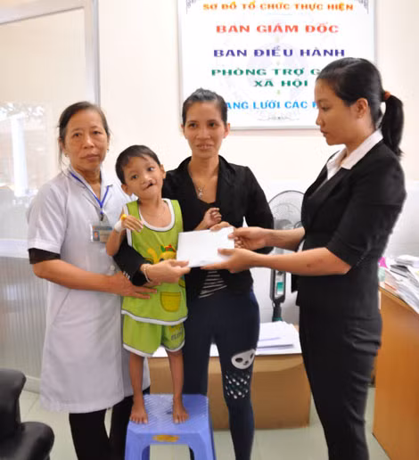Đại diện gia đình cụ bà Nguyễn Thị Chiến (bên phải) trao tiền hỗ trợ cho gia đình 2 bé Gia Huỳnh và Trọng Nguyễn tại Phòng trợ giúp XH- BV Nhi Đồng 1 trưa ngày 28/9