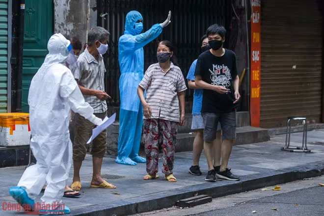 Hướng dẫn người dân xếp hàng, từng nhóm 5 người rồi được nhân viên y tế vào nhà đưa ra lấy mẫu.
