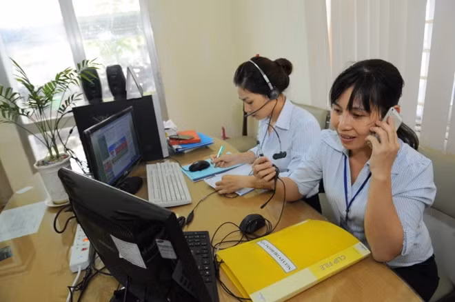 Chị Đoàn Thị Lệ Quyên (trái) và Mai Thị Thanh Lam trực đường dây nóng trả lời thắc mắc và hướng dẫn người dân làm thủ tục hành chính tại UBND quận 8 - Ảnh: Tự Trung