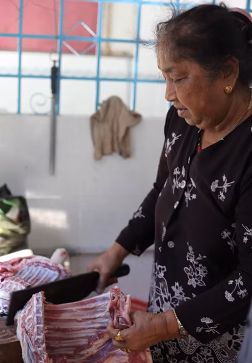 Bà Fatima Beevi, con gái ông B. Ahamad, đang bán thịt dê cho khách hàng.