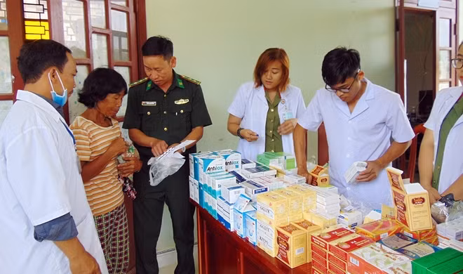 Cán bộ biên phòng hỗ trợ hướng dẫn bằng tiếng đồng bào Cơ tu cách sử dụng thuốc cho bà con.