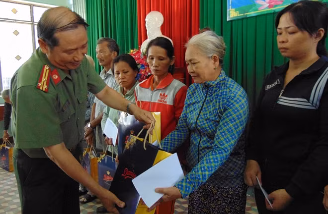 Thượng tá Nguyễn Văn Long, Trưởng VPTT Báo CAND tại miền Trung, tặng quà cho hộ gia đình chính sách.