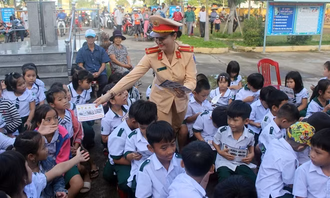 Tuyên truyền viên phát tờ rơi cho các em học sinh.
