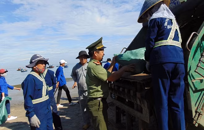 Đoàn viên thanh niên Công an thu gom rác trên bãi biển đưa lên xe rác.