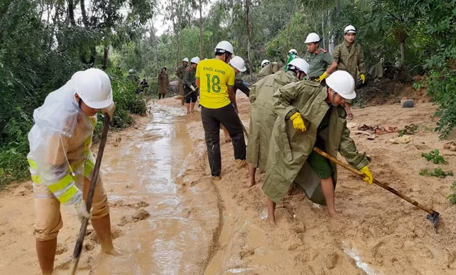 Đào bới đất đá, thu dọn bùn nước để khai thông hai đoạn đường bị sạt lở, bồi lấp ở xã Xuân Lâm, thị xã Sông Cầu
