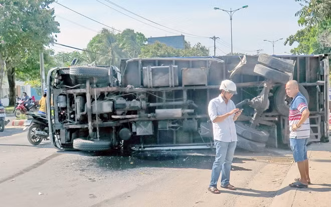 Một trong hai xe ô tô tải lật nghiêng trên mặt đường