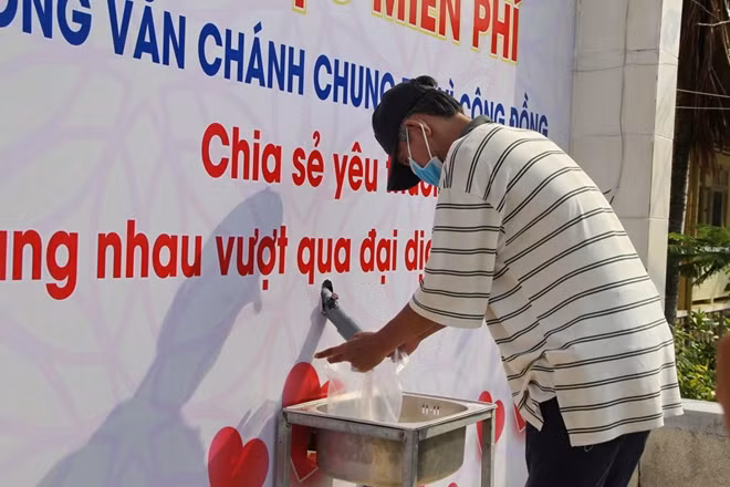 Người dân nhận gạo từ máy "ATM gạo" của Trường THPT chuyên Lương Văn Chánh. Ảnh : Hữu Toàn