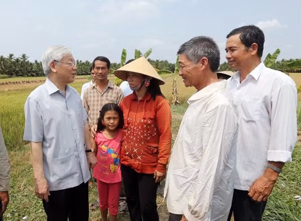Tổng Bí thư Nguyễn Phú Trọng thăm hỏi nông dân trên cánh đồng lúa bị xâm nhập mặn ở xã Tân Thanh, huyện Giồng Trôm. Ảnh: TTXVN.