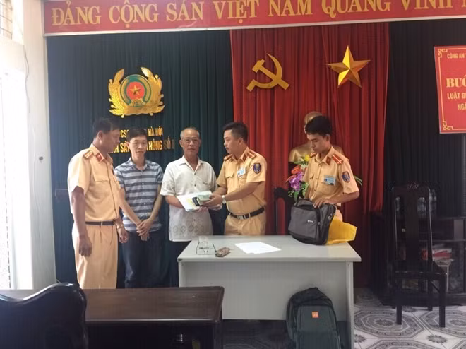Đại diện Đội CSGT số 8 trao trả lại số tiền và giấy tờ cho ông Hạnh