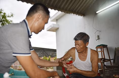 Võ sư Lý Xuân Hỷ đắp thuốc cho thanh niên bị trật tay.