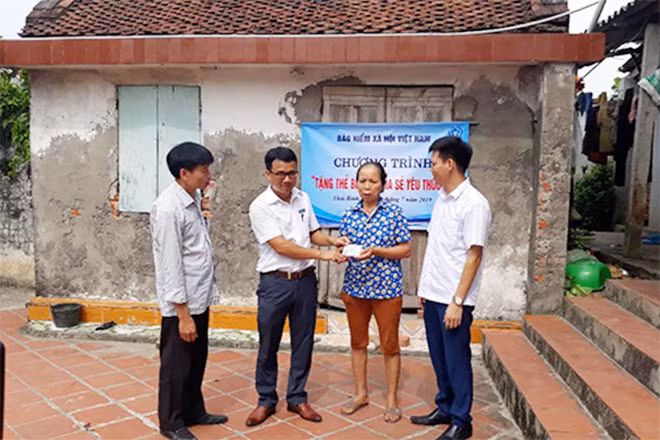 Đại diện lãnh đạo BHXH huyện Thái Thụy, Thái Bình trao thẻ BHYT cho người dân.