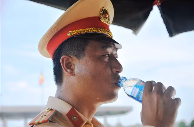 Ngoài trời quá nắng nóng khiến gương mặt các đồng chí CSGT không lúc nào ngớt mồ hôi và liên tục phải sử dụng nước uống.