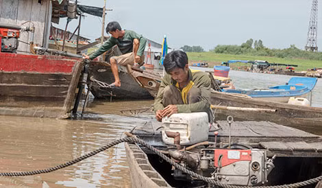 Hai người đàn ông này đang sửa máy chiếc ghe chở cá thuê. Đó là cách duy nhất họ kiếm tiền sau khi cá nuôi bị chết.