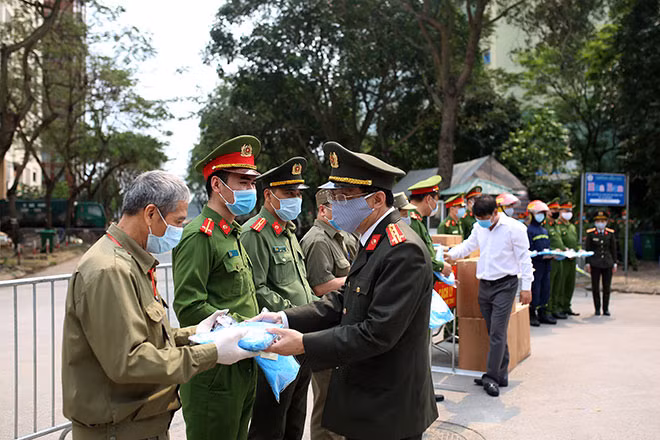 Đại tá Phạm Quang Khải và ông Thái Quang Trung trao bộ đồ bảo hộ y tế tặng cán bộ, chiến sĩ thực thi nhiệm vụ phòng, chống dịch tại khu cách ly tập trung ở Pháp Vân - Tứ Hiệp, quận Hoàng Mai.