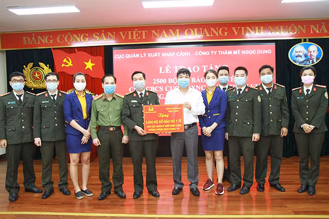 Phó Tổng biên tập báo CAND Trần Thanh Phong và đại diện Công ty TNHH Thẩm mỹ Ngọc Dung trao tặng quà cho Cục Quản lý xuất nhập cảnh.