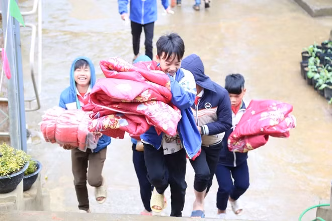Các em học sinh vui mừng đón nhận những tấm chăn ấm của Đoàn công tác tặng.