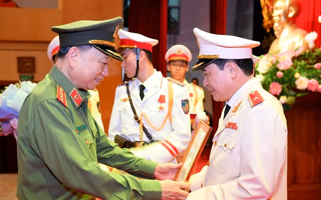 Bộ trưởng Tô Lâm trao quyết định và tặng hoa chúc mừng tân Thứ trưởng Lê Quốc Hùng.