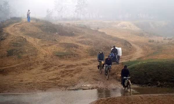 Những người buôn lậu nhiên liệu đi xe đạp và xe máy băng qua dòng suối ở khu vực biên giới Nepal và Ấn Độ.