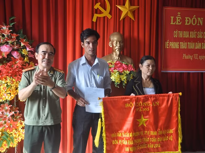 Thừa ủy quyền của Bộ trưởng Bộ Công an, Đại tá Phan Văn Hùng, Phó Giám đốc Công an tỉnh Hậu Giang trao Cờ thi đua xuất sắc của Bộ Công an tặng nhân dân, cán bộ phường 7, TP.Vị Thanh