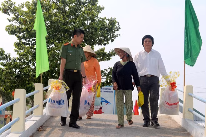 Thiếu tá Nguyễn Văn Bình cùng ông Lưu Quốc Cường động viên bà con xã Lương Tâm cố gắng phấn đấu vươn lên trong cuộc sống.