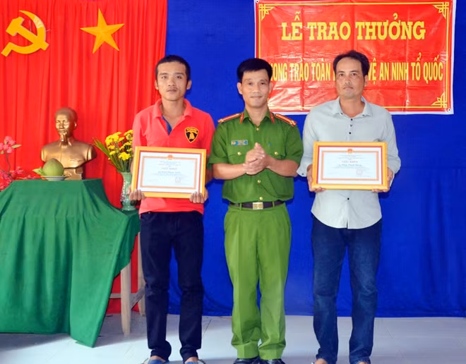 Đại diện Công an huyện Chợ Lách trao giấy khen cho anh Phong và anh Nghĩa.