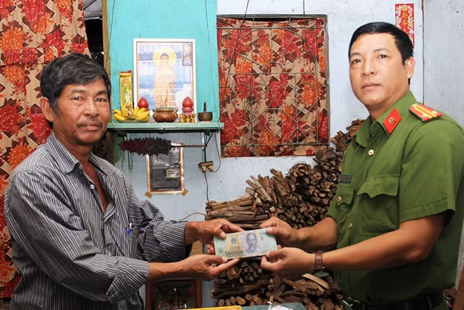 Đại diện Công an phường Mỹ Long bàn giao lại số tiền 50 triệu đồng cho ông Đỗ Văn Hướng