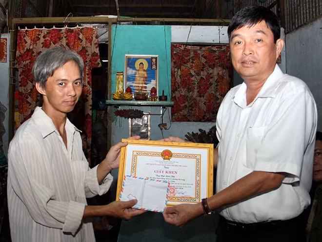 Đại diện UBND phường Mỹ Long trao tặng giấy khen cho anh Ngô Liên Tấn.