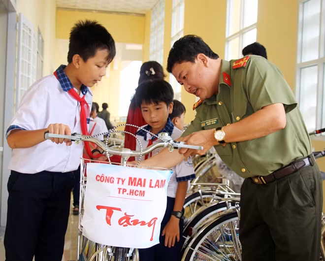 Đại diện Báo CAND hướng dẫn các em cách sử dụng xe đạp.