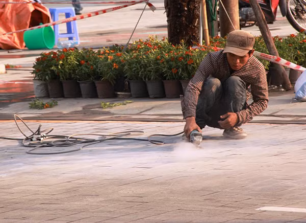Mặt đường chính của quảng trường đi bộ đang được các công nhân làm sạch bụi bẩn.