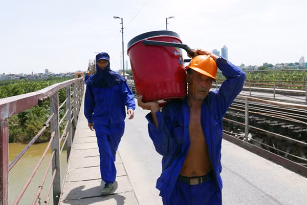 Công nhân sơn cầu Long Biên chuẩn bị thùng nước lạnh lớn để uống trong khi làm việc.