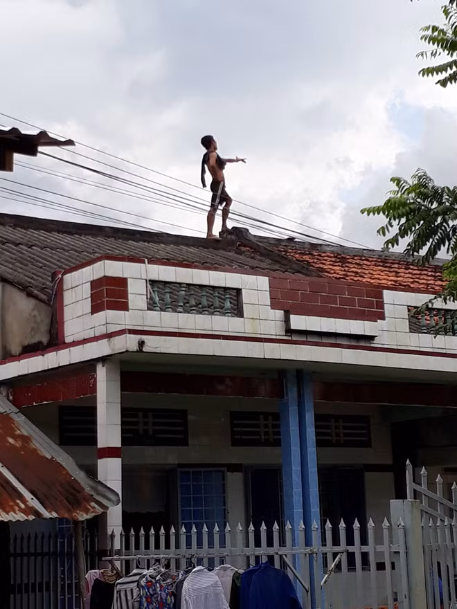 Đối tượng nghi "ngáo đá" vẫn đang cố thủ trên nóc nhà hơn 7 tiến đồng qua.