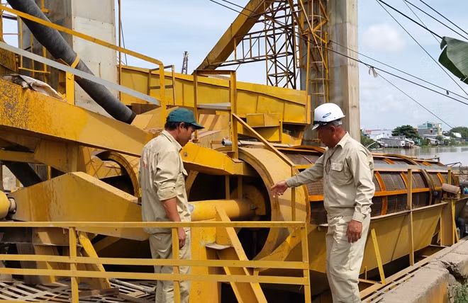 Ông Võ Tấn Dũng (bên phải), chỉ đạo công nhân vận hành dây chuyền sản xuất cát sạch.