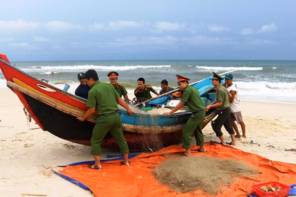 Cán bộ, chiến sĩ Công an Quảng Bình giúp ngư dân đẩy thuyền lên bờ tránh bão.