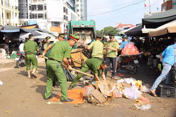 Công an phường Hồng Sơn, TP Vinh cùng Ban Quản lý chợ Vinh dọn dẹp rác thải ngay trước cổng chợ.