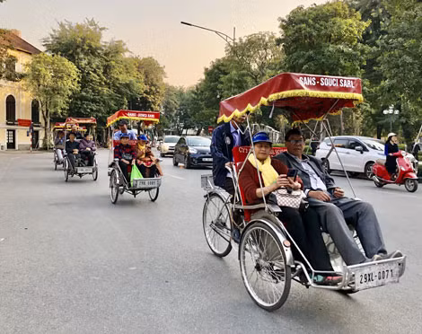 Du khách nước ngoài trải nghiệm đi xe xích lô quanh hồ Hoàn Kiếm.