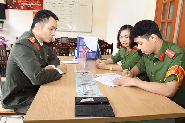 Trung úy Triệu Quý Tư (Bên trái) trình báo và giao nộp chiếc ví cho Công an phường Đồng Tâm, TP Yên Bái để xác minh tìm trả người đánh mất.