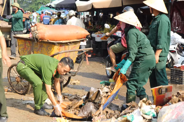 Công an phường Hồng Sơn cùng công nhân vệ sinh môi trường thành phố Vinh dọn dẹp hàng chục tấn rác thải phía trước chợ Vinh.