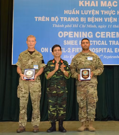 Đại tá Hoàng Kim Phụng tặng quà lưu niệm các trưởng đoàn chuyên gia quân y của Hoa Kỳ và Vương quốc Anh.
