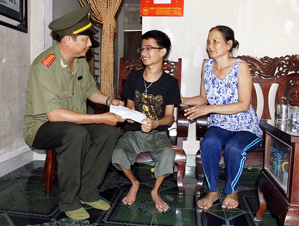 Trung tá Nguyễn Văn Long- Phó Ban Thư ký, Trưởng Văn phòng thường trú Báo CAND tại Miền Trung trao số tiền hỗ trợ cho em Tín.