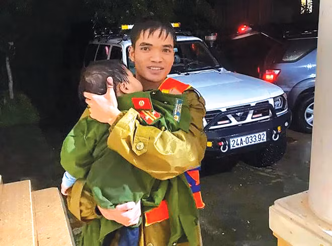 Cháu bé trong vòng tay chiến sĩ CAND khi được cứu trên chiếc xe khách có 20 người bị lũ cuốn trôi tại Quảng Bình.