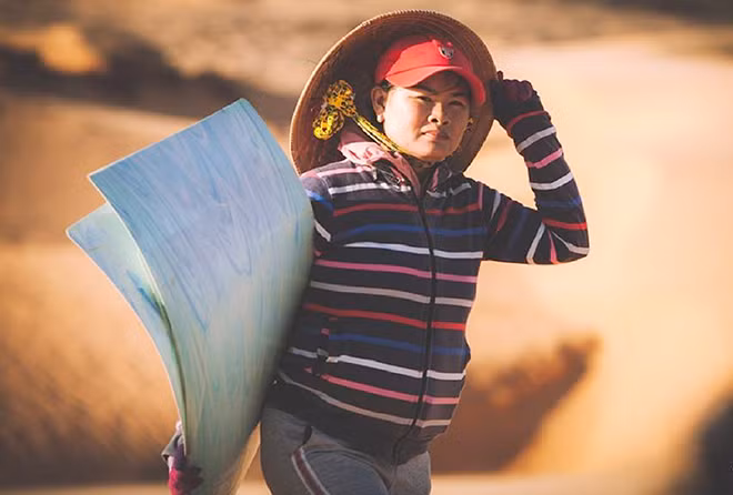Một phụ nữ cho thuê ván trượt trên triền cát.