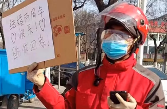 Anh Trương mắt về người vợ, giơ cao tấm biển ""Chúc mừng kỷ niệm hai năm ngày cưới của chúng ta, mong em về".