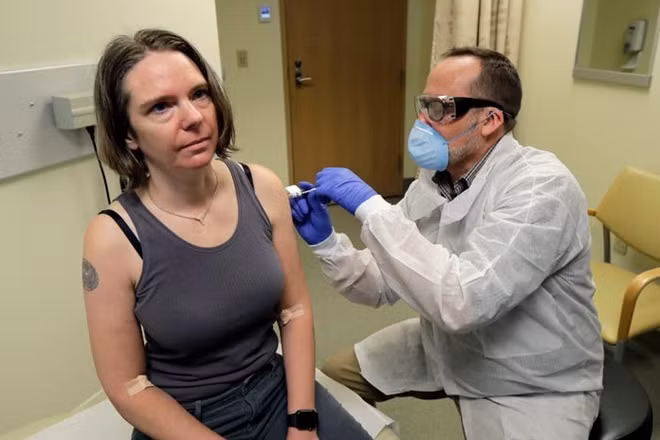 Trong ngày 16/3, có 4 người khỏe mạnh tại Mỹ là những người đầu tiên được tiêm vaccine COVID-19. Trong ảnh là một bác sĩ tiêm mũi vaccine cho tình nguyện viên Jennifer Haller. Đây là mũi tiêm đầu tiên trong thử nghiệm lâm sàng giai đoạn đầu của vaccine COVID-19.