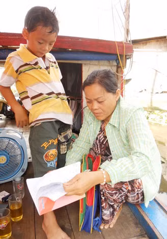 Lão đi quăng chài, vợ ở trên thuyền chăm lo các cháu.