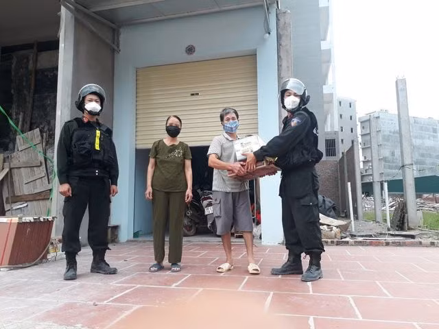 Cán bộ Công an Bắc Giang trao quà cho người dân bị cách ly.