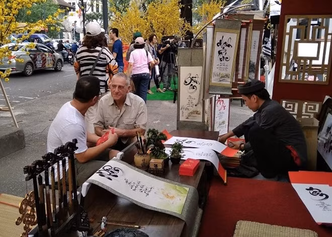 Một người nước ngoài đang được giải thích về thú xin chữ ngày tết của người dân Việt Nam
