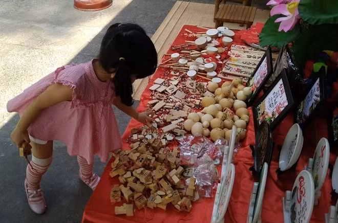 Một em bé thích thú khi cùng mẹ dạo phố ông đồ