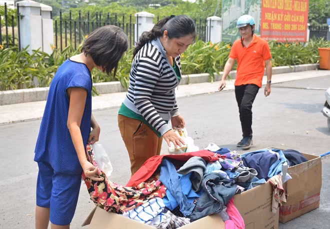 Một số cư dân sống tạm ở một chung cư đang thi công bên cạnh lựa quần áo miễn phí để mặc