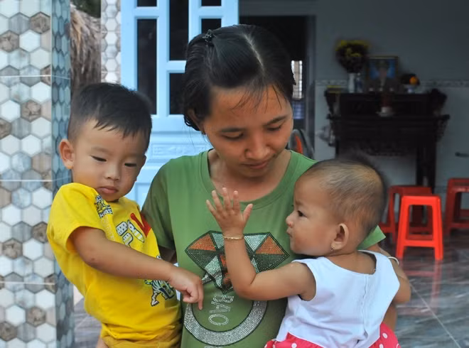 Hai đứa con nhỏ của liệt sĩ đại úy Phạm Phi Long quấn quýt bên mẹ