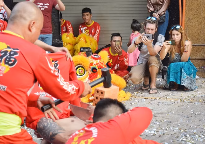 Hai người nước ngoài thích thú khi xem đoàn lân biểu diễn các tiết mục công phu